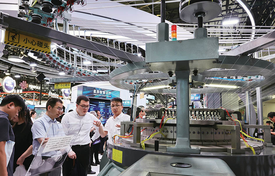 2025年7月26日,参观者在一个依托大模型数据打造的星辰纺织智能体展品旁交流讨论 方喆摄/本刊 2025年7月26日,参观者在一个依托大模型数据打造的星辰纺织智能体展品旁交流讨论 方喆摄/本刊