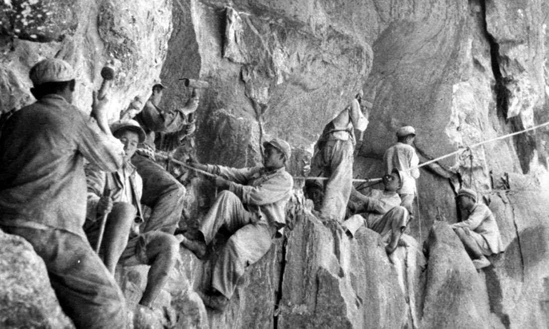 1954年，修筑康藏公路的解放軍戰(zhàn)士們在怒江兩岸的懸崖陡壁上辟山筑路。新華社稿 李萬春、張加里攝
